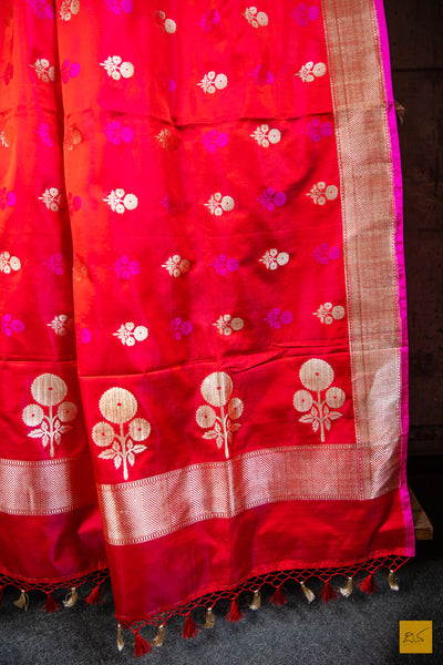 Designed with a stunning red and pink hue, this luxurious SAMANVITA saree is crafted from handwoven mashru banarasi silk and highlighted with intricate zari and pink buttas. Its supremely soft drape will feel exquisite against your skin and is complete with a shimmering brocade blouse. Exquisite and exclusive, this saree is the ultimate expression of luxury.  Fabric- Mashru silk  Colour- Red and pink