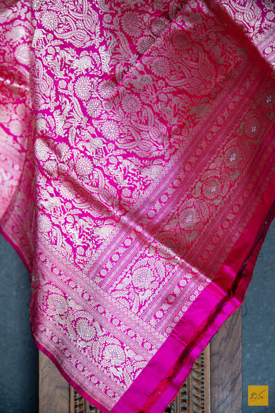 A PADMARAGA Banarasi Katan Silk Handwoven Saree is the pinnacle of luxury for those seeking a timeless and elegant look. This beautiful saree features intricate shikargah border and koniya that add a touch of sophistication to your wardrobe. Its soft texture and easy draping make it perfect for any special occasion. A shikargah blouse is adding to the beauty of this saree.  Fabric- Katan silk  Colour- Pink
