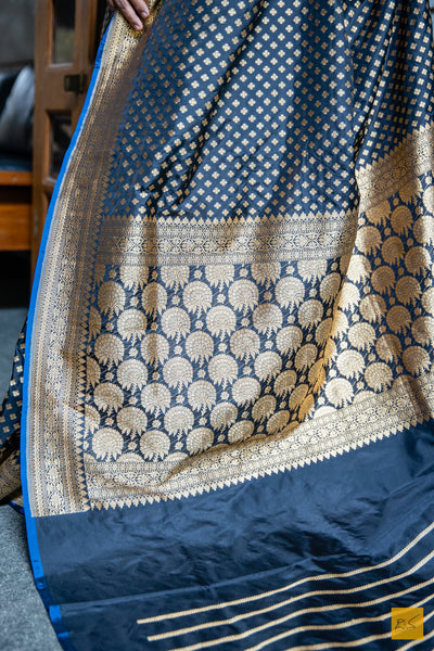 MUKTHAA Black Banarasi Katan Silk Saree is crafted with timeless elegance. Its soft material is easy to drape, while small buttas woven in cutwork style lend a charming look. Perfect for special occasions, this handwoven saree adds a classic touch to your wardrobe.