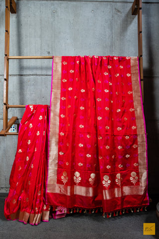 Designed with a stunning red and pink hue, this luxurious SAMANVITA saree is crafted from handwoven mashru banarasi silk and highlighted with intricate zari and pink buttas. Its supremely soft drape will feel exquisite against your skin and is complete with a shimmering brocade blouse. Exquisite and exclusive, this saree is the ultimate expression of luxury.  Fabric- Mashru silk  Colour- Red and pink