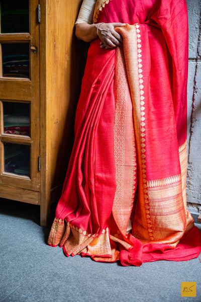 Experience the opulence of a classic Red Banarasi Tussar Silk Saree. Handwoven to perfection for unparalleled comfort, this timeless piece of art is designed to be light and airy for an effortless drape, while its classic styling exudes a subtle elegance. A truly distinguished and luxurious garment.