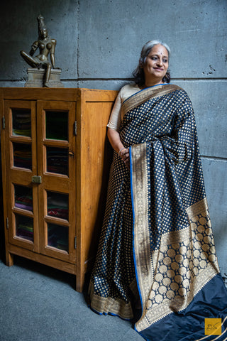 MUKTHAA Black Banarasi Katan Silk Saree is crafted with timeless elegance. Its soft material is easy to drape, while small buttas woven in cutwork style lend a charming look. Perfect for special occasions, this handwoven saree adds a classic touch to your wardrobe.