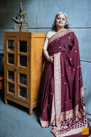 MADHURYA Banarasi Georgette Handwoven Saree makes an exquisite addition to any wardrobe. Combining timeless and classy designs with intricate silver meenakari in the border and pallu, and delicate kadhwa buttas, this saree is a perfect choice for any formal or informal occasion. Soft and easy to drape, the MADHURYA Banarasi Georgette Handwoven Saree is sure to make you look and feel elegant.  Fabric- Georgette  Colour- Rust Brown