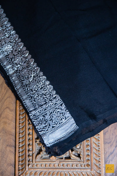 Make a statement in this black beauty Lavanya Banarasi Georgette Handwoven Saree. Exquisitely crafted with silver zari kadhwa motifs, this luxuriously soft saree is designed to perfectly drape for a beautiful silhouette. Ideal for both formal and informal occasions, this timeless piece of art is sure to turn heads.  Fabric- Georgette
