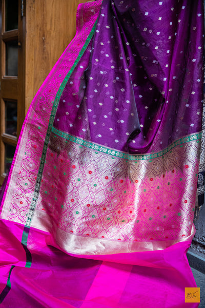 This NANDITHA banarasi kora silk organza saree is a luxurious piece of art. Pristinely handwoven and detailed with a stunning meenakari border and pallu, it is a sheer elegance for any special occasion. Its intricate small motifs add a delicate beauty, making it an effortlessly chic and eye-catching piece. Gracefully drape it around and be the centre of attention.  Fabric- Kora silk Organza  Colour- Purple and Pink