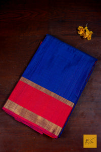 Blue and red saree with a gold border on a dark brown background