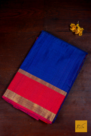 Blue and red saree with a gold border on a dark brown background