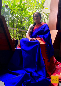 Vagdevi is a handwoven dupion silk sari in dark blue and red. Adorned with a traditional temple border, this sari is perfect for special occasions and festivities. The combination of beautiful colors and intricate weaving make this sari a timeless piece of art.