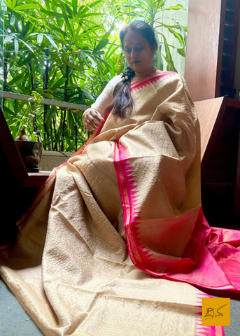 Adorn yourself with this stunningly beautiful Vidyunmala saree. Crafted from the finest Tussar silk, decorated with a chequered zari body, a pink contrast, and a stunning temple border, this handwoven saree will ensure you make a striking impression.