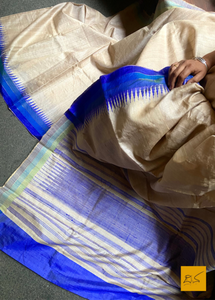 Experience the exquisite craftsmanship of Saumya, a handwoven tussar silk saree with a chequered zari body and a temple border in blue contrast. Delicately constructed for a timeless look, Saumya is a must-have in your wardrobe.  Fabric-Tussar Silk.